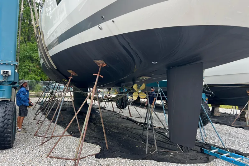  Yacht Photos Pics 2023 Jeanneau 65 yacht on stands, undergoing maintenance, with visible propeller and keel.