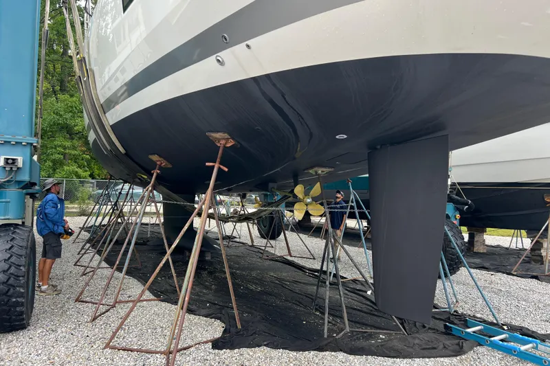  Yacht Photos Pics 2023 Jeanneau 65 yacht on stands, undergoing maintenance, with visible propeller and keel.