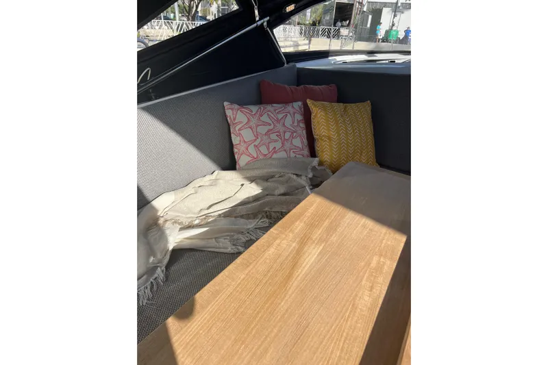  Yacht Photos Pics Cozy seating area on 2023 Jeanneau 65 yacht with colorful cushions and wooden table.