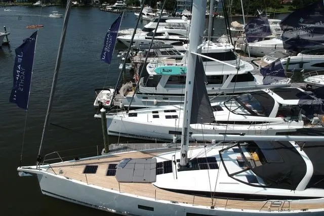  Yacht Photos Pics 2023 Jeanneau 65 yacht docked at marina with other boats, showcasing sleek design and modern features.