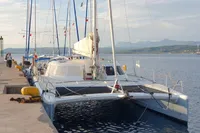 2001 Catamaran NIMBLE 50 docked at a scenic harbor with mountains in the background.