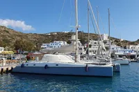 2001 Catamaran NIMBLE 50 docked in a scenic marina with hillside buildings.