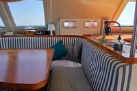 Interior of 2001 Catamaran NIMBLE 50 with striped seating and wooden table.