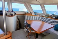 Interior of 2001 Catamaran NIMBLE 50 with striped seating and wooden table, ocean view.