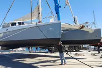 Catamaran NIMBLE 50, 2001 model, being lifted at a marina with clear blue skies.
