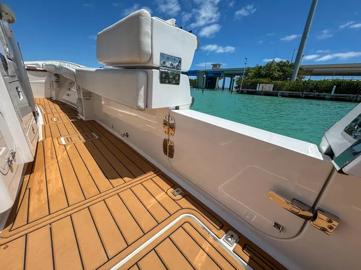 Aquamarine Yacht Photos Pics 2019 HCB 39 Speciale boat with teak deck, docked by turquoise water under blue sky.