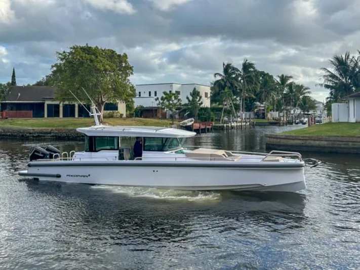  Yacht Photos Pics 2024 Axopar 37XC CROSS CABIN boat cruising on a calm waterway.