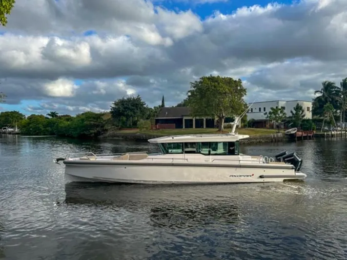  Yacht Photos Pics 2024 Axopar 37XC CROSS CABIN boat on a serene river with cloudy sky.