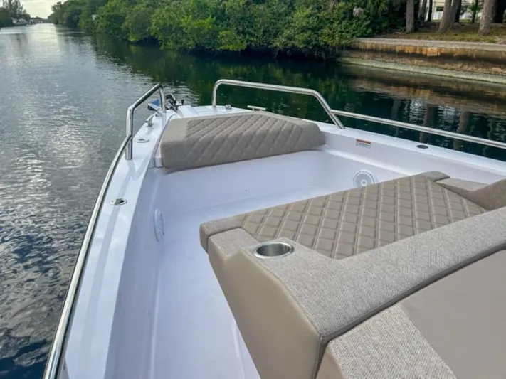  Yacht Photos Pics 2024 Axopar 37XC CROSS CABIN boat with cushioned seating on a calm waterway.