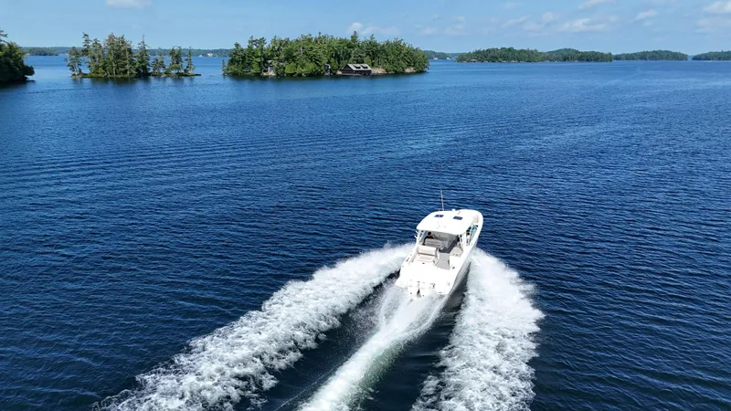  Yacht Photos Pics 2019 Boston Whaler 320 Vantage cruising on a serene lake with lush islands.