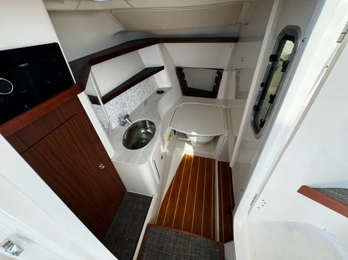 None Yacht Photos Pics 2022 Grady-White Freedom 325 boat interior with sink, toilet, and wood accents.