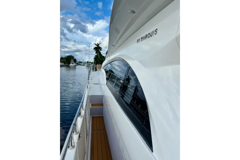  Yacht Photos Pics 2004 Marquis 59 yacht on a serene waterway under a partly cloudy sky.