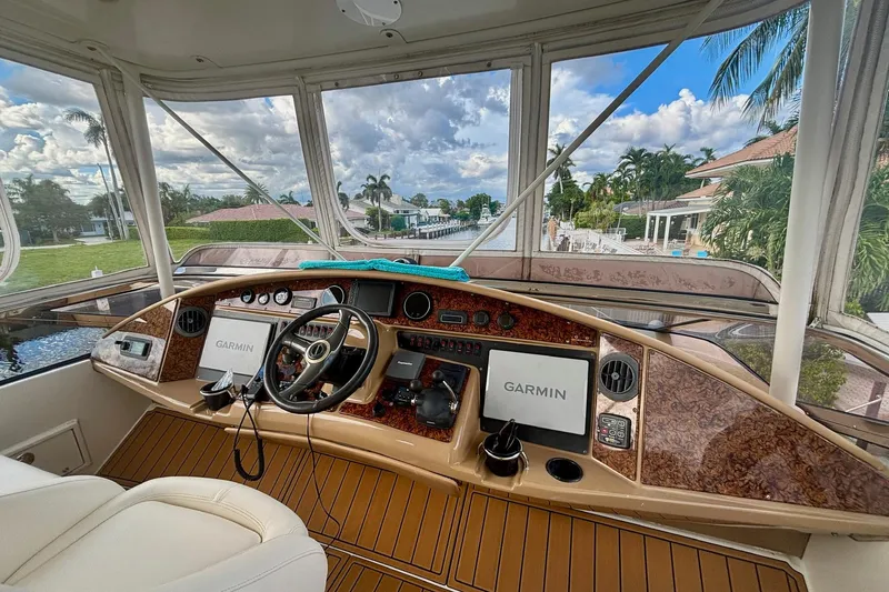  Yacht Photos Pics 2004 Marquis 59 yacht helm with Garmin navigation, luxurious wood finish, and waterfront view.