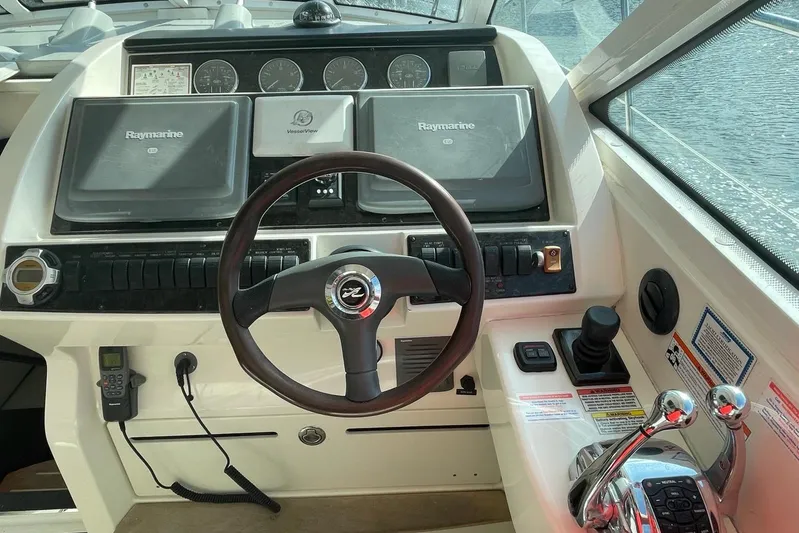 Beach House Yacht Photos Pics Control panel of a 2010 Sea Ray 450 Sundancer boat with steering wheel and navigation equipment.