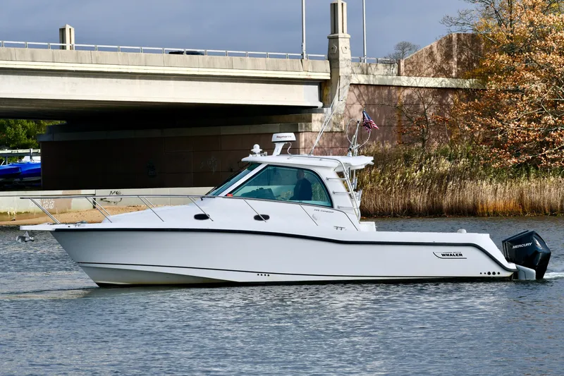  Yacht Photos Pics 2011 Boston Whaler 345 Conquest boat on calm water near a bridge.