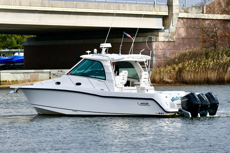  Yacht Photos Pics 2011 Boston Whaler 345 Conquest boat cruising under a bridge on a calm waterway.