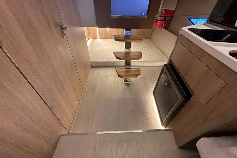  Yacht Photos Pics Modern interior of 2025 NX Boats 370 with wooden steps and compact kitchen.