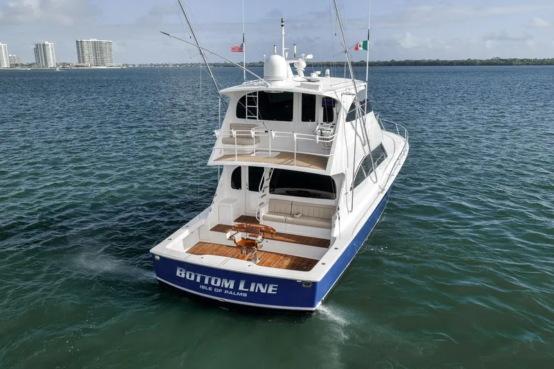 Bottom Line Yacht Photos Pics 2012 Viking 60 Enclosed Bridge yacht on open water, rear view with city skyline.