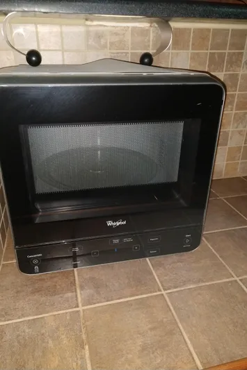 Elizabeth Rose Yacht Photos Pics Compact black microwave on tiled kitchen counter, featuring Whirlpool branding.