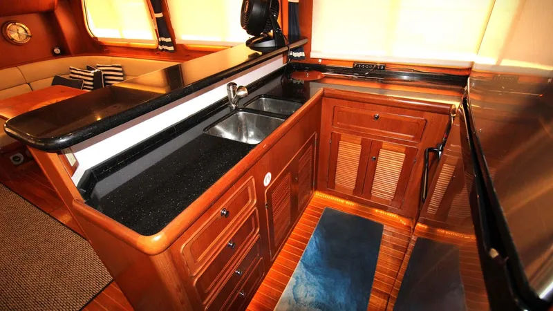 The Concession Yacht Photos Pics Luxurious kitchen area in a 2001 Selene 53 Pilothouse yacht with wood cabinetry and black countertops.