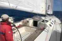 Sailor navigating a 2005 Finot Open 50 yacht on open sea.