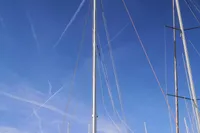 Sailboat with red sail, Finot Open 50, 2005 model, docked under clear blue sky.