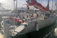 Sailboat docked at marina, Finot Open 50, 2005 model, with red sail cover.