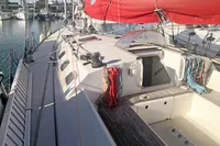 Sailboat deck of 2005 Finot Open 50 with red sail, docked in marina.