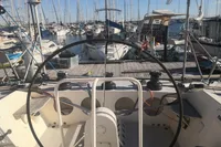Cockpit view of 2005 Finot Open 50 sailboat in a marina, surrounded by other boats.