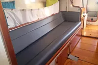 Interior of 2005 Finot Open 50 sailboat with cushioned seating and wooden flooring.
