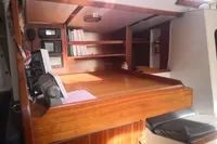 Navigation station in 2005 Finot Open 50 yacht with wooden desk and electronic equipment.
