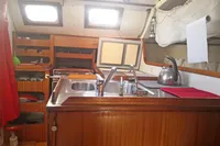 Interior of 2005 Finot Open 50 sailboat with wooden cabinetry and kitchen area.