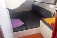 Cozy cabin interior of 2005 Finot Open 50 sailboat with cushions and colorful pillows.