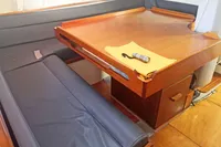 Interior of 2005 Finot Open 50 sailboat with wooden table and blue seating.