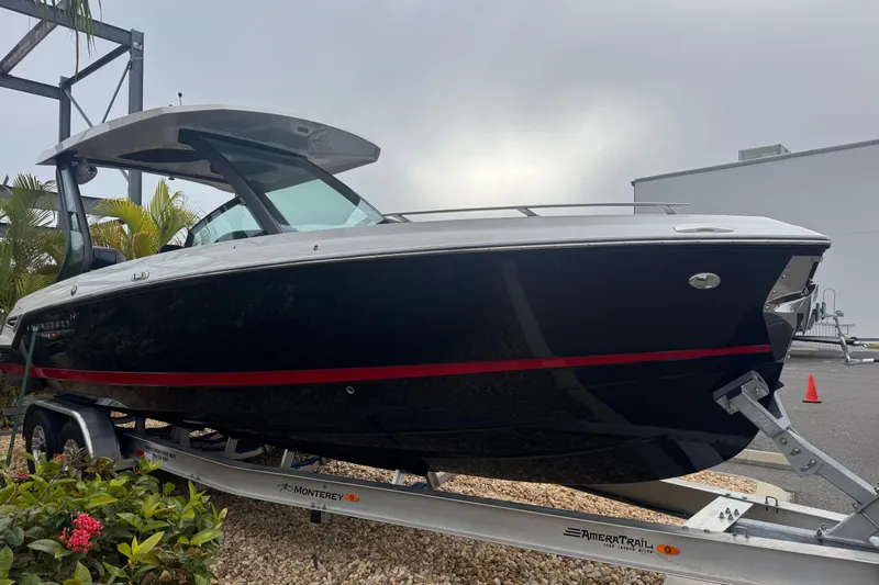  Yacht Photos Pics 2025 Monterey Elite 27 OB boat on trailer, sleek design, black hull, red stripe.