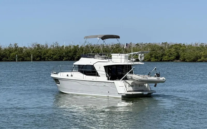 Seven Grand Yacht Photos Pics 2016 Beneteau Swift Trawler 30 on calm water, surrounded by lush greenery.