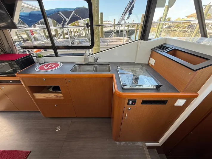 Seven Grand Yacht Photos Pics 2016 Beneteau Swift Trawler 30 kitchen with sink, stove, and wooden cabinetry.