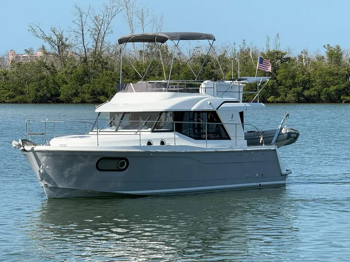 Seven Grand Yacht Photos Pics 2016 Beneteau Swift Trawler 30 cruising on calm waters with lush greenery in the background.