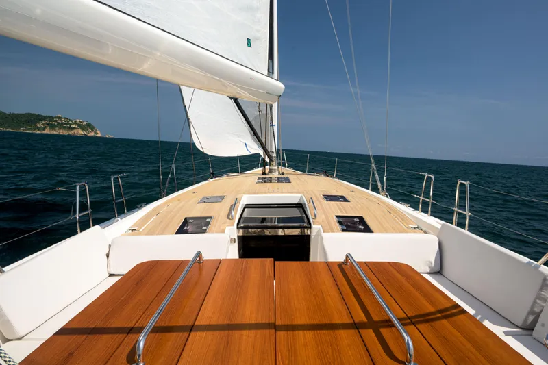 Invictus Yacht Photos Pics 2023 Nautor Swan 55 yacht sailing on open sea with wooden deck and white sails.