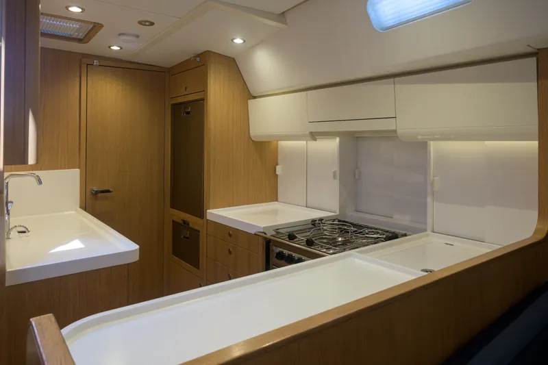Invictus Yacht Photos Pics Modern kitchen interior of 2023 Nautor Swan 55 yacht, featuring sleek wood and white finishes.