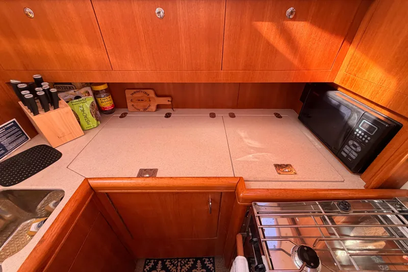 Thursday's Child Yacht Photos Pics Galley kitchen in 2005 Hunter Passage 456 yacht with microwave and wooden cabinetry.