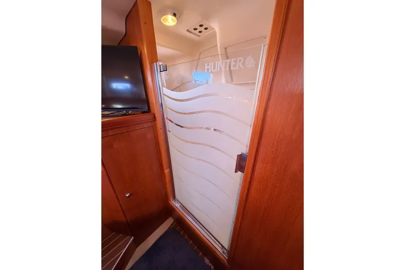 Thursday's Child Yacht Photos Pics Interior of 2005 Hunter Passage 456 yacht with wooden cabinetry and frosted glass door.