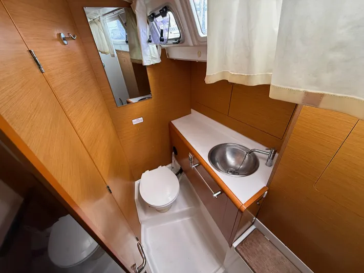 Corrine Yacht Photos Pics 2015 Jeanneau 409 yacht bathroom with wooden cabinetry, sink, and toilet.