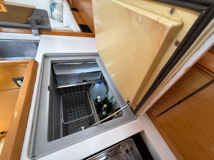 Corrine Yacht Photos Pics Jeanneau 409 yacht interior with open fridge, showcasing beverages and storage space.