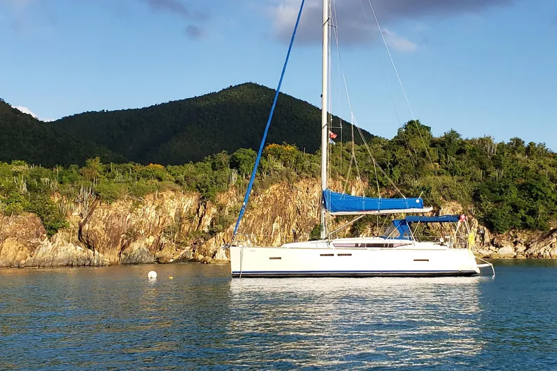 Corrine Yacht Photos Pics 2015 Jeanneau 409 sailboat anchored near rocky shoreline and lush greenery.