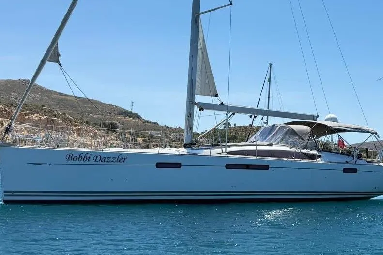 Bobbi Dazzler Yacht Photos Pics 2013 Jeanneau 57 sailboat "Bobbi Dazzler" on calm blue water, scenic background.