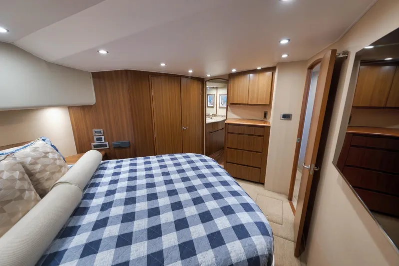 Even Flow Yacht Photos Pics Luxurious 2009 Viking Convertible yacht bedroom with checkered bedding and wooden cabinetry.
