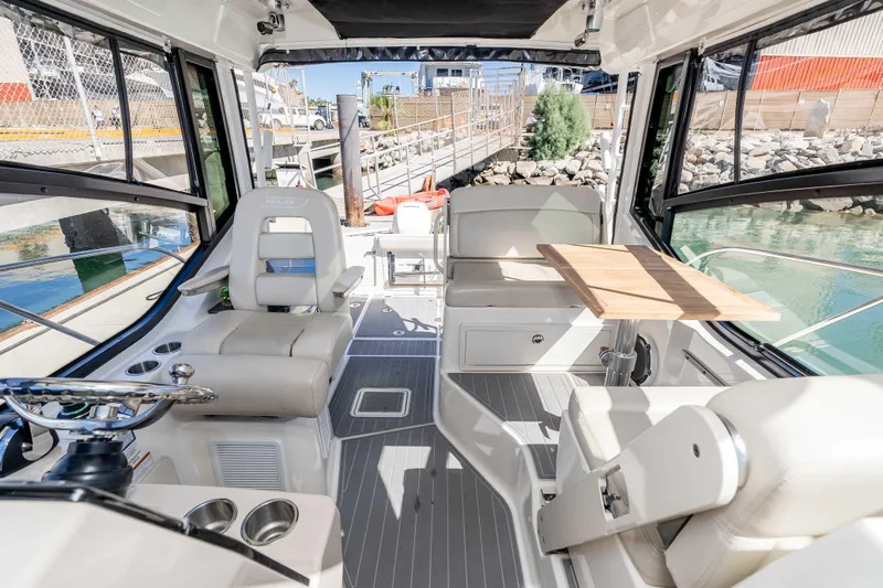 A Day In The Life Yacht Photos Pics 2021 Boston Whaler 325 Conquest interior with seating, table, and helm, docked by the water.