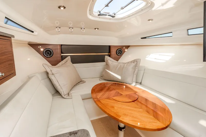 A Day In The Life Yacht Photos Pics 2021 Boston Whaler 325 Conquest cabin with elegant seating and wooden table.
