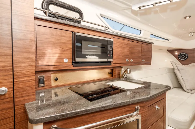 A Day In The Life Yacht Photos Pics 2021 Boston Whaler 325 Conquest interior kitchen with microwave, stove, and sink.